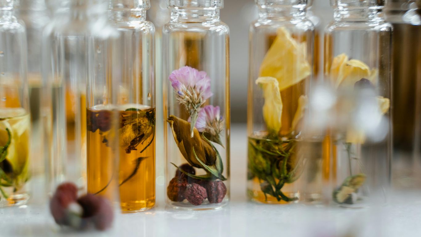 Glass vials filled with dried flowers and amber liquid, arranged closely.