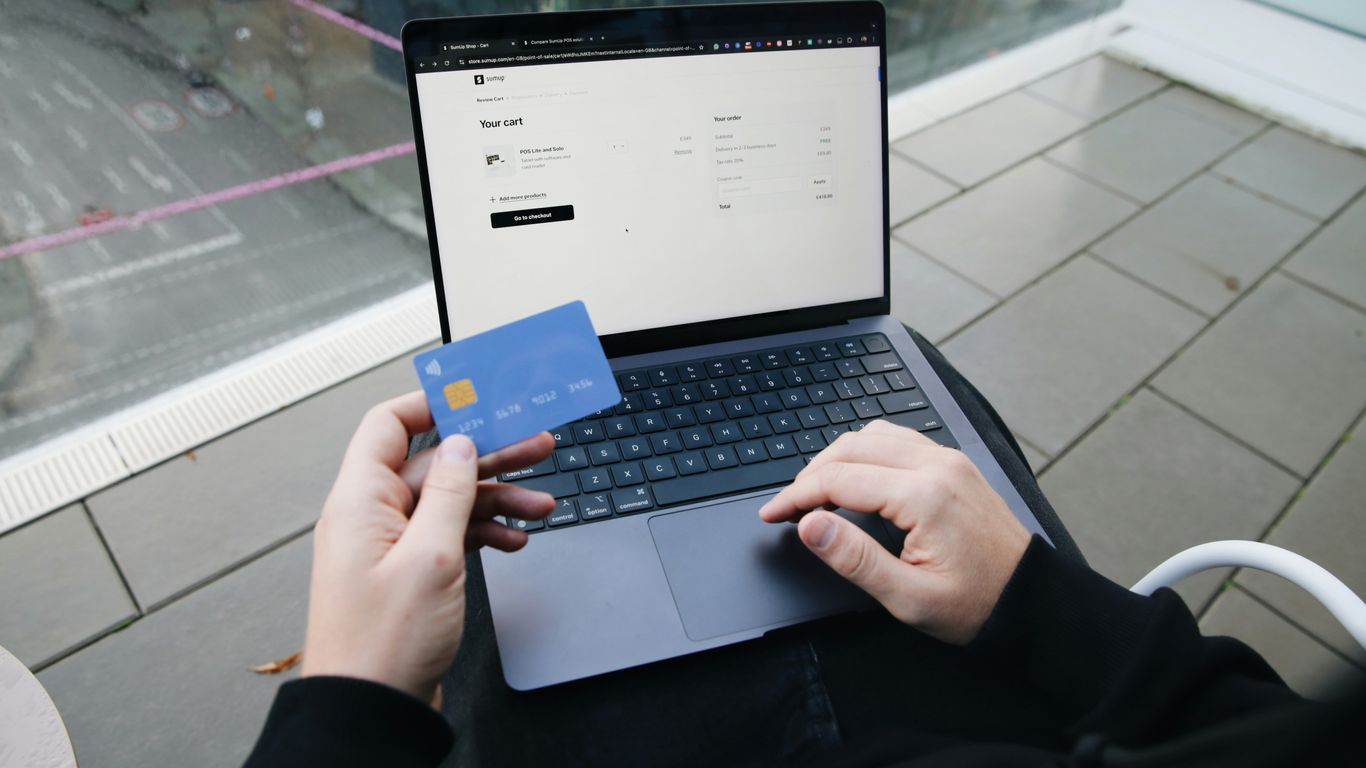 A person sitting in a chair with a laptop and a credit card