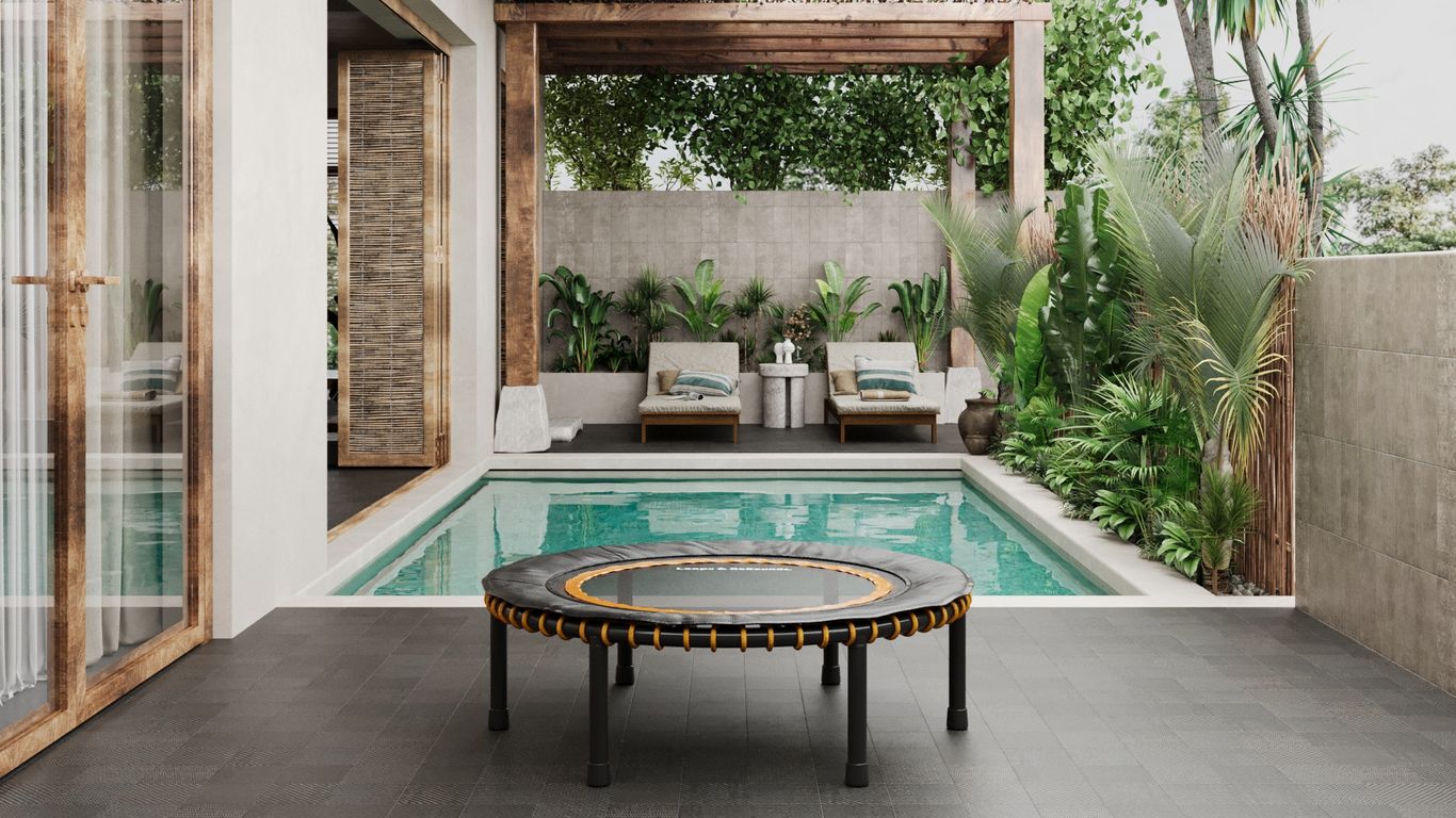 Modern patio with pool, trampoline, lounge chairs, and lush plants.