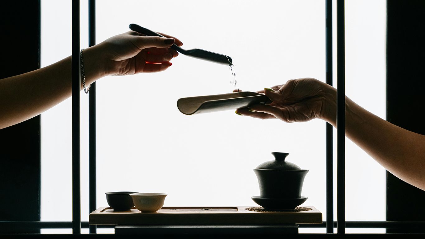 Hands performing a tea ceremony with water pouring.