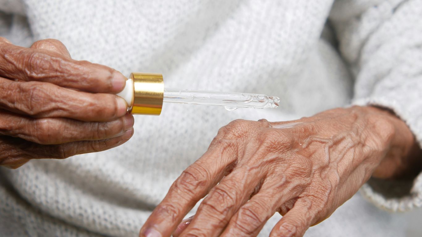 an older woman holding a small tube of liquid