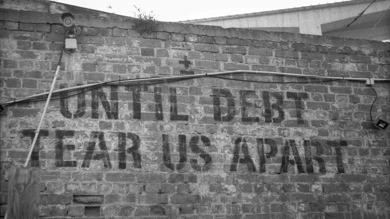 a sign on a brick wall that says until debt tears apart