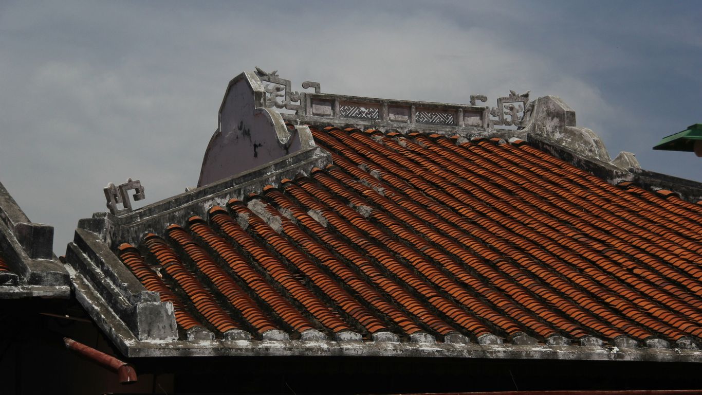 Traditional tiled roof with decorative gables, showcasing intricate architectural details and weathered texture, relevant to attic ventilation discussions.