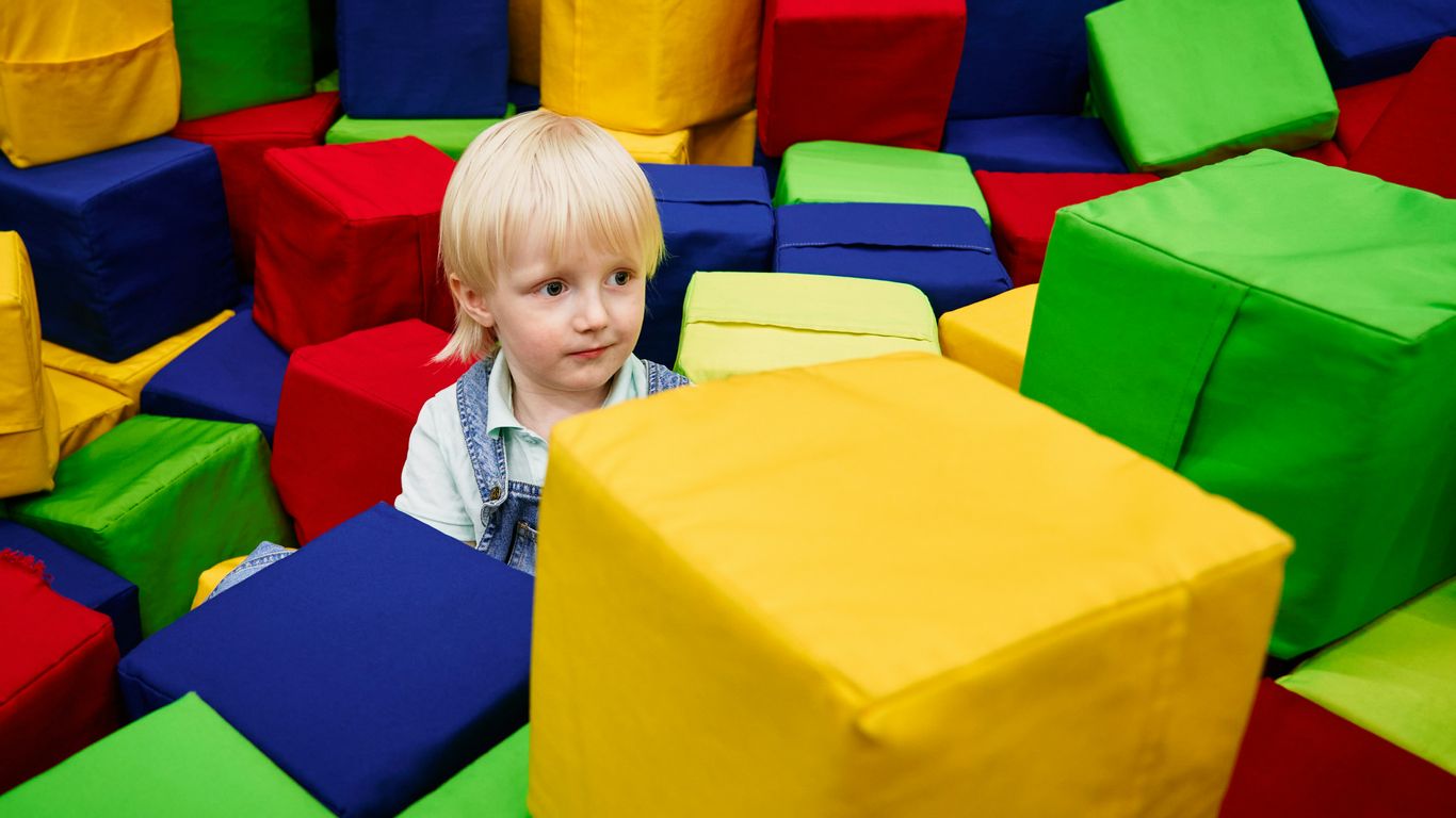 a child sitting in a large pile of colorful plastic toys