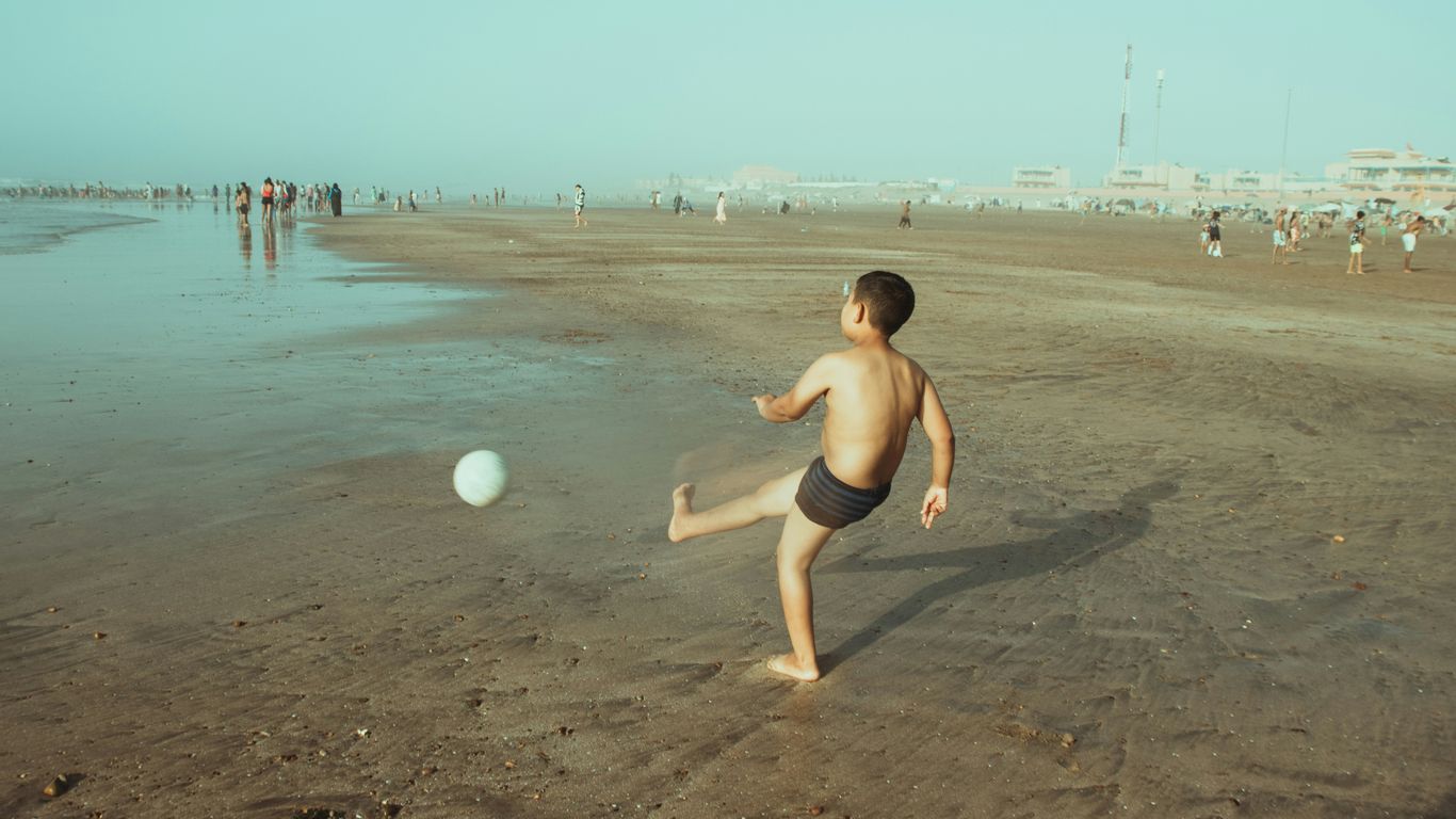 A young boy playing with a ball on the beach