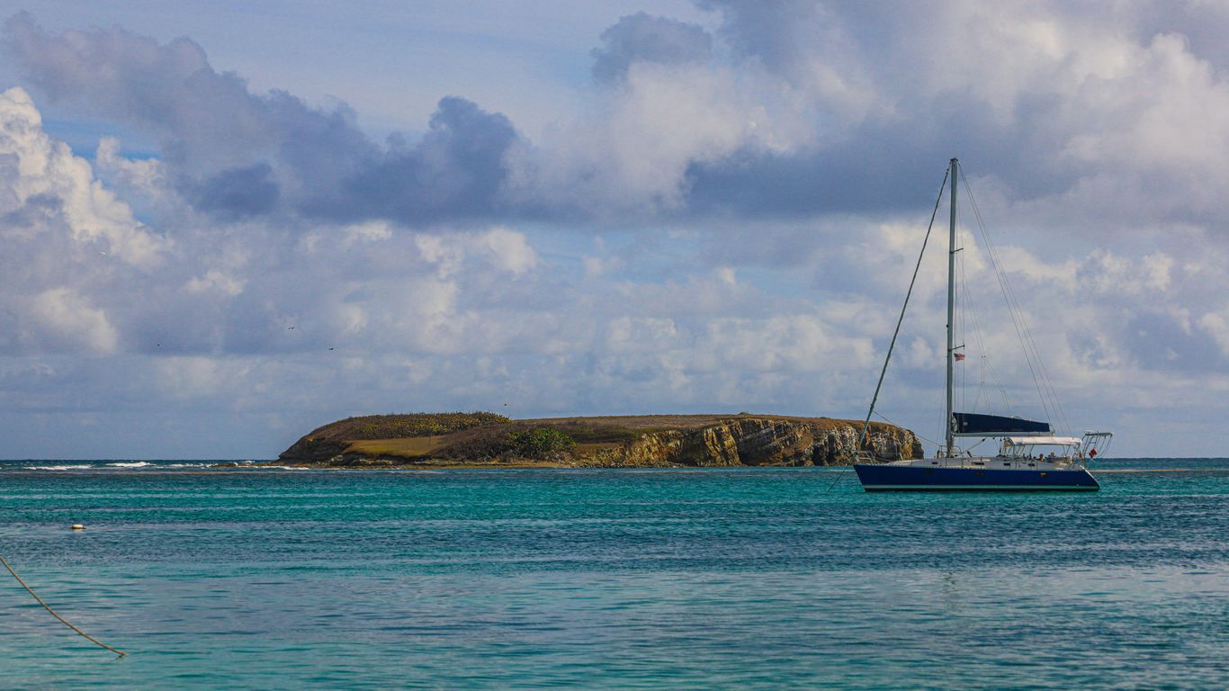 white sailboat on sea under white clouds and blue sky during daytime