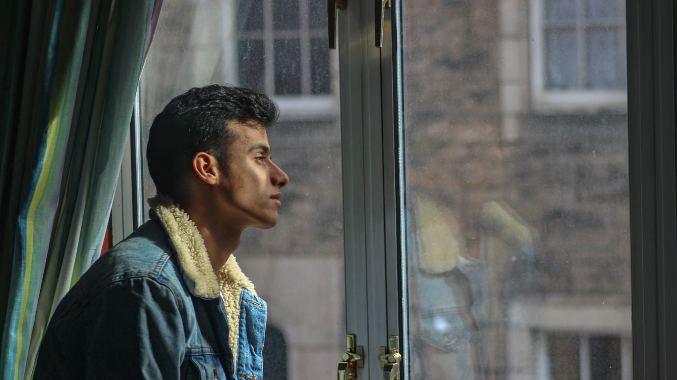 man in black jacket looking out the window