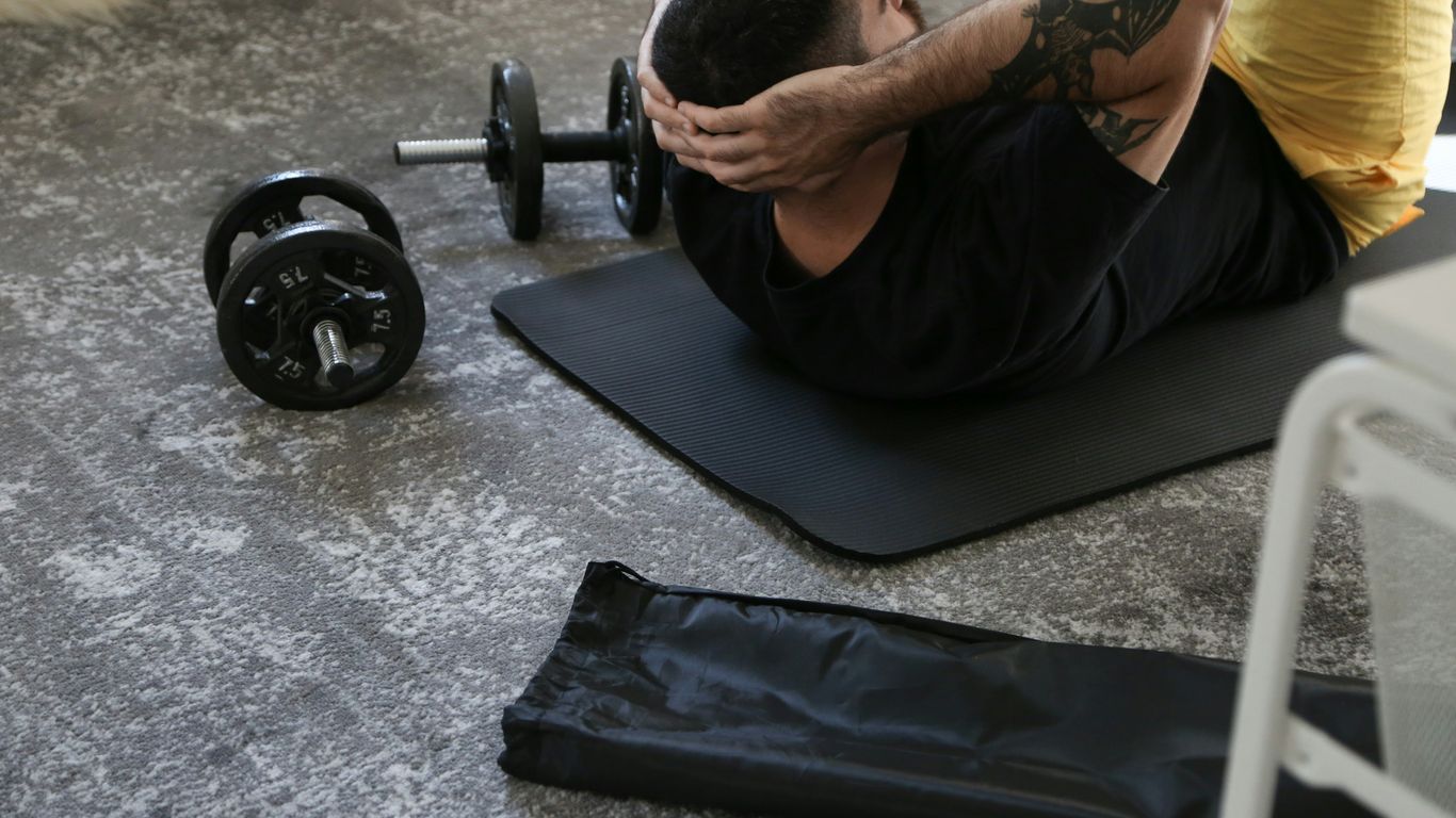 a man is doing exercises on a mat with a barbell