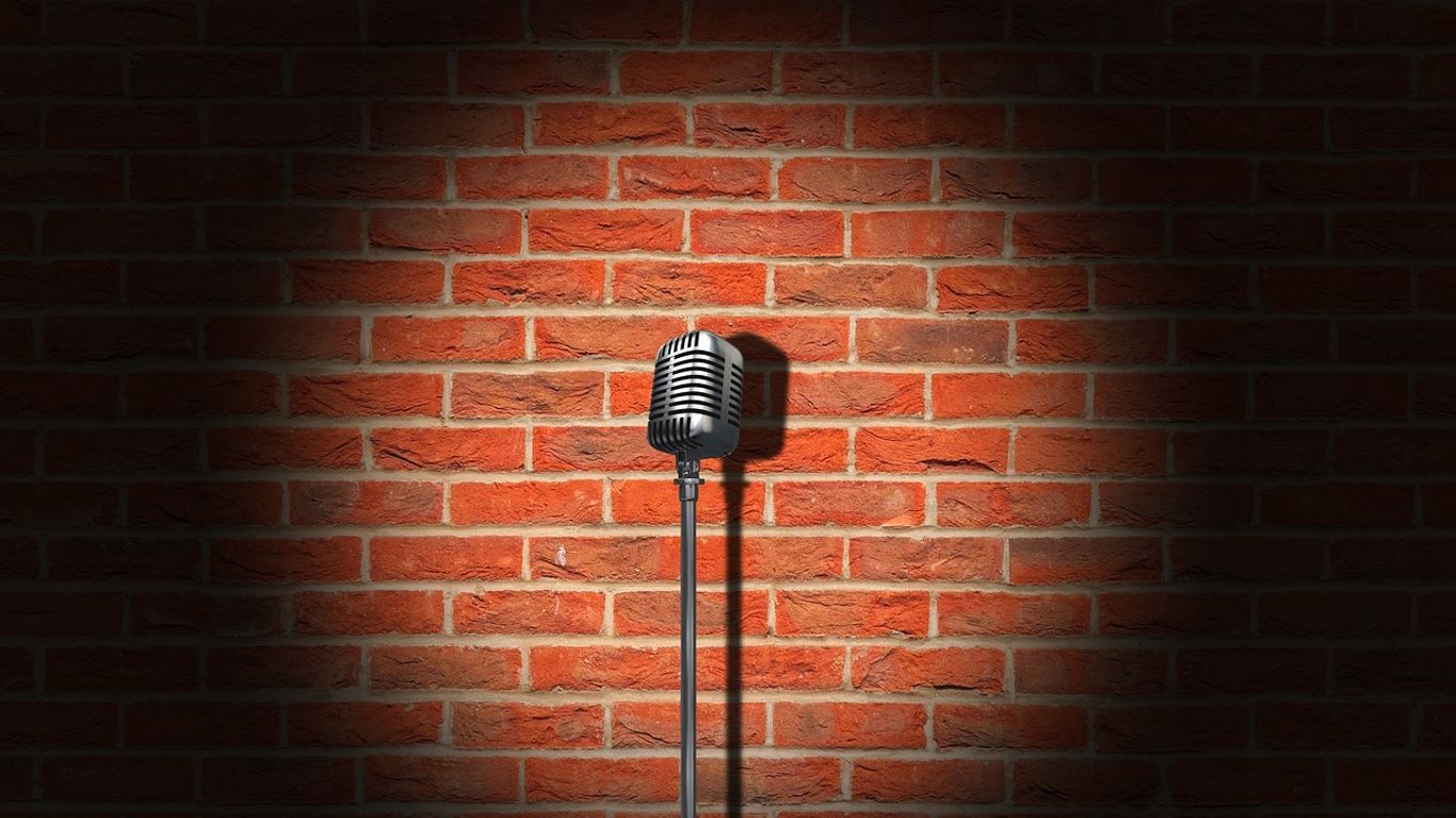 A classic microphone illuminated against a brick wall backdrop.