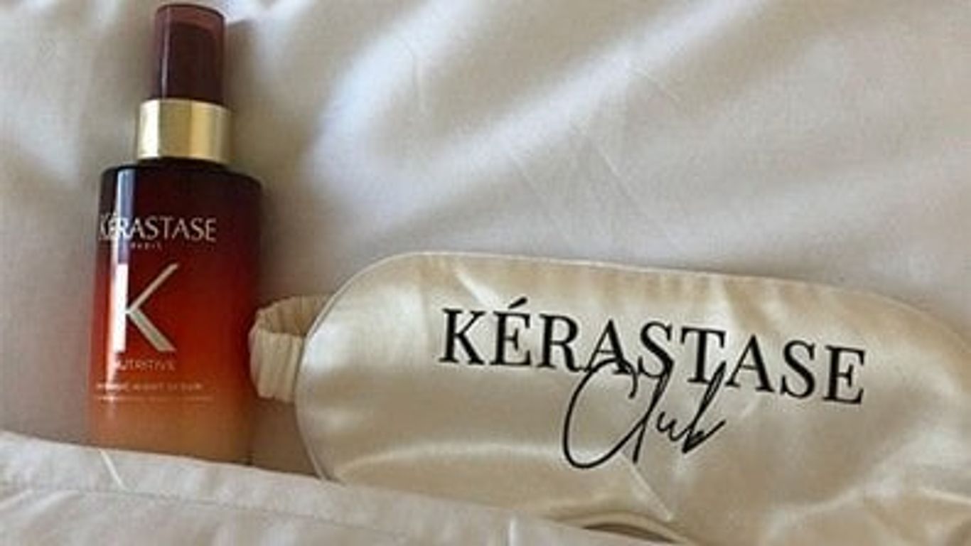 Haircare product and branded sleep mask on white fabric.