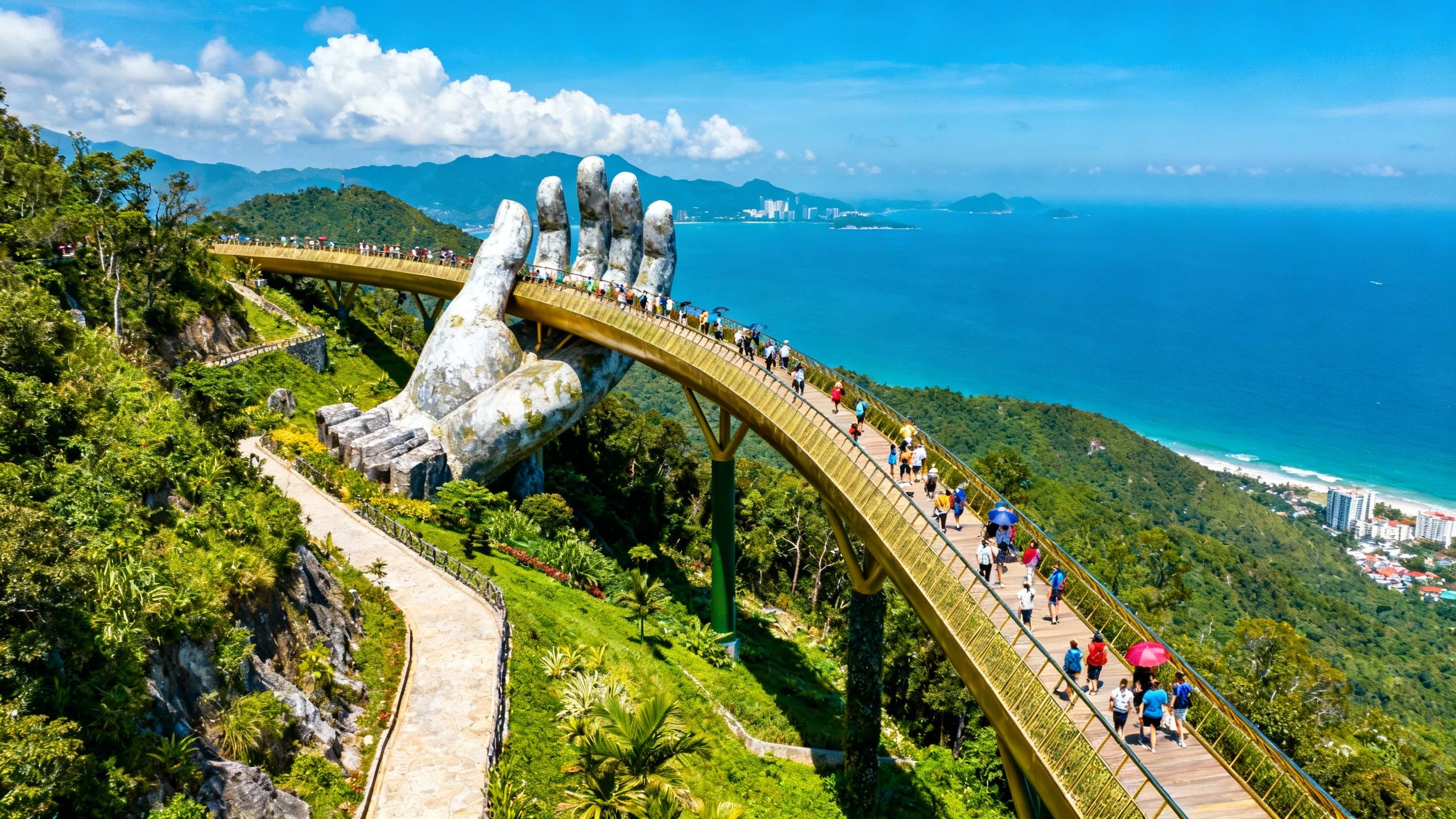Golden Bridge in Da Nang, Vietnam, held by stone hands over hills.