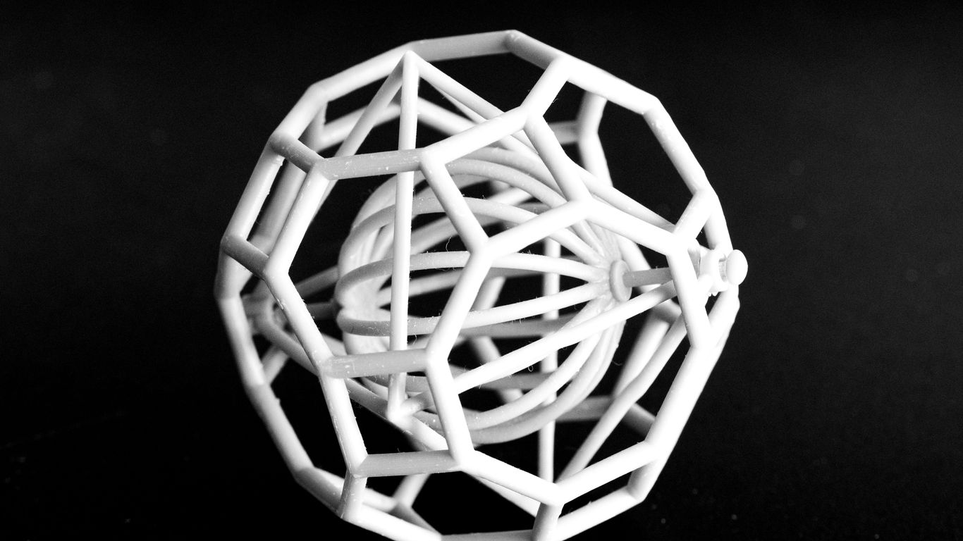 A white geometric sculpture on a black surface.