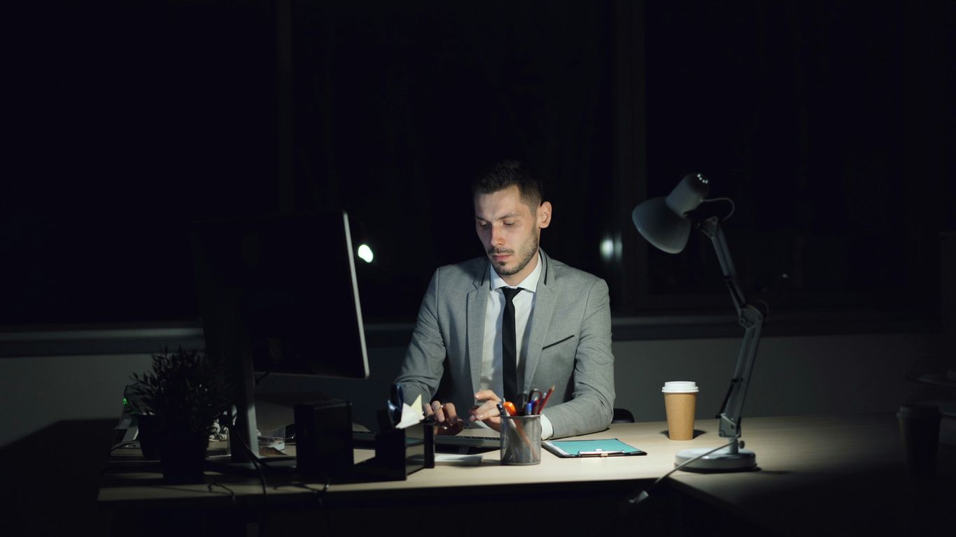 Man working late at his desk with coffee.