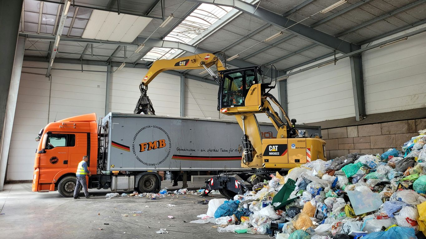 a large truck with a load of trash in a warehouse