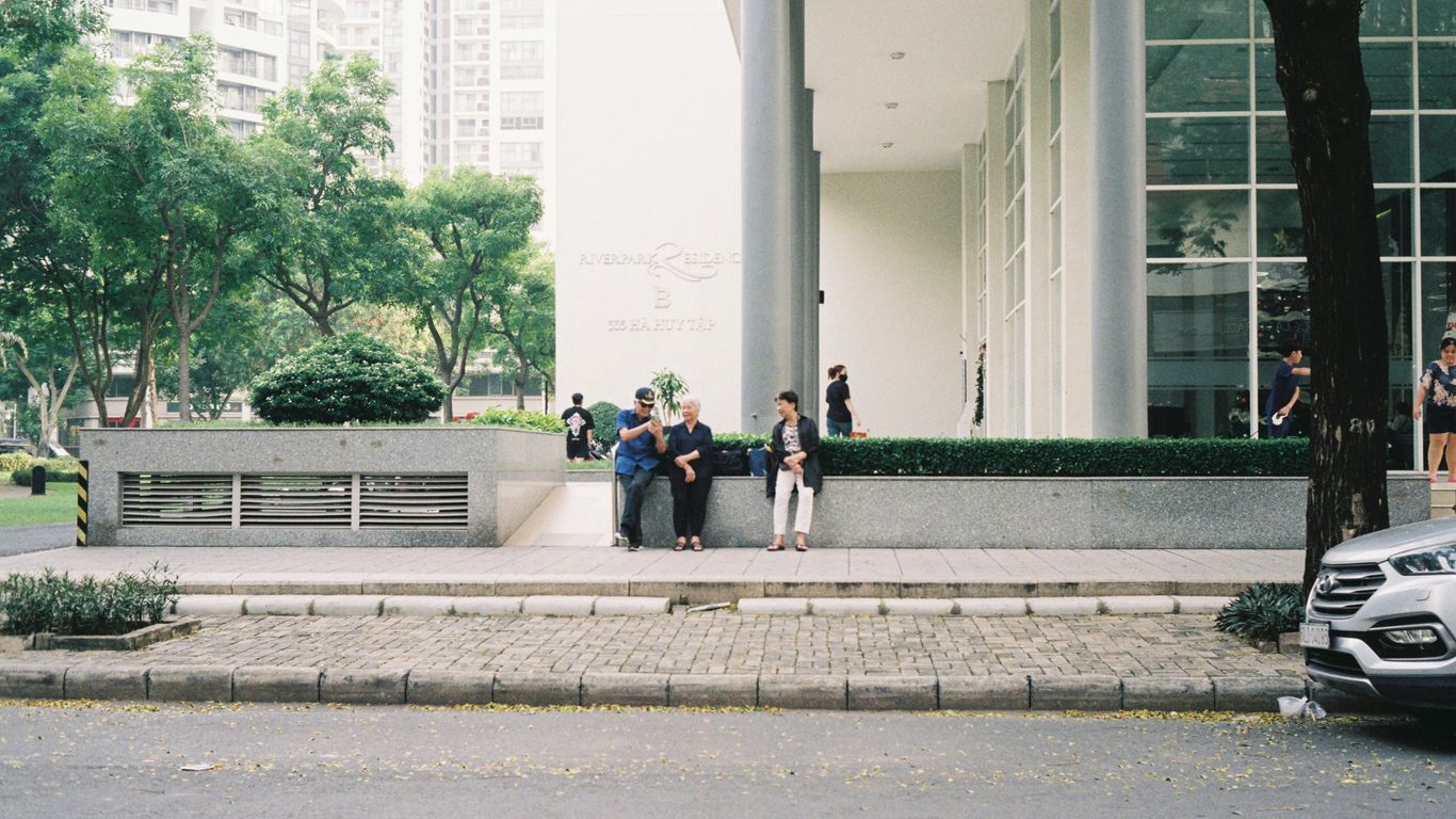 A group of people sitting on a bench in front of a building