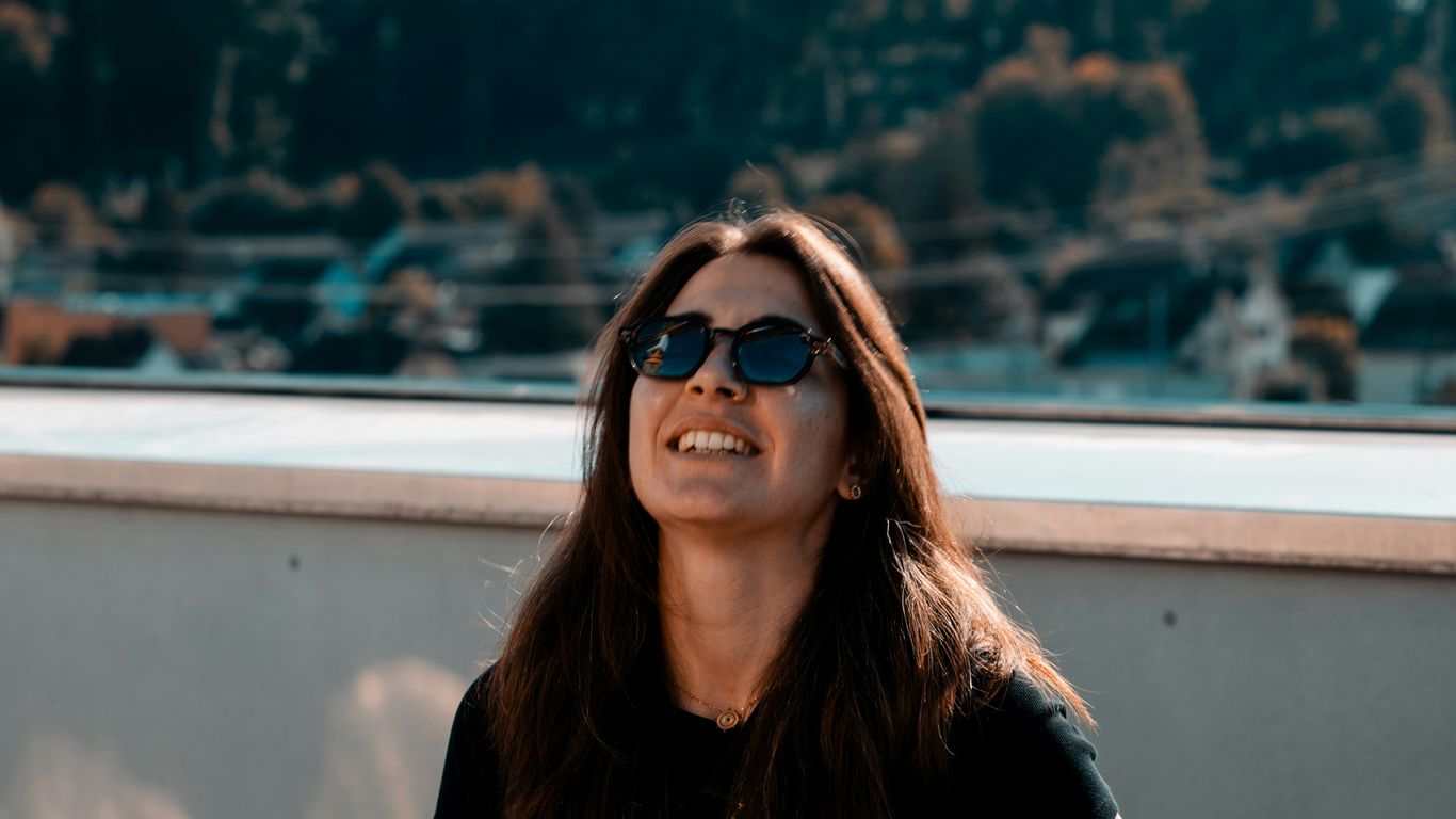 A woman wearing sunglasses sitting on a ledge
