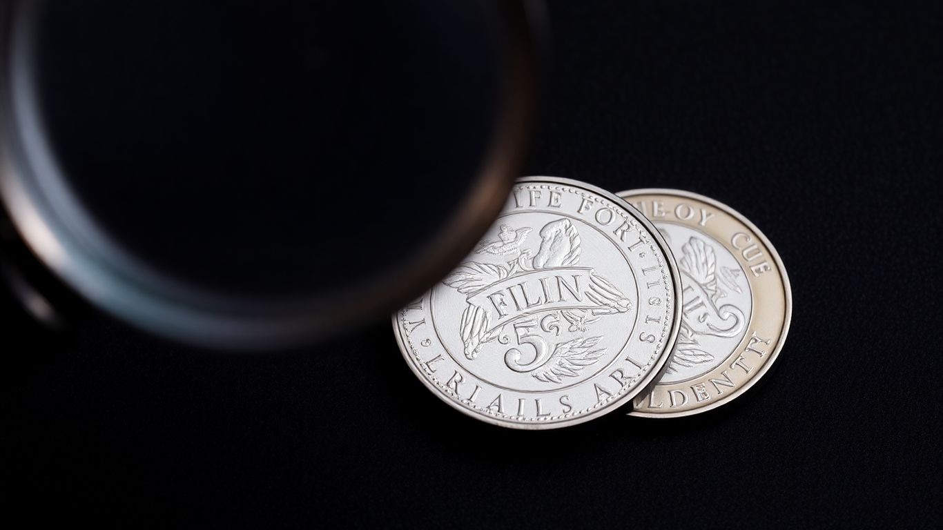 Magnifying glass inspecting a silver coin for authenticity.