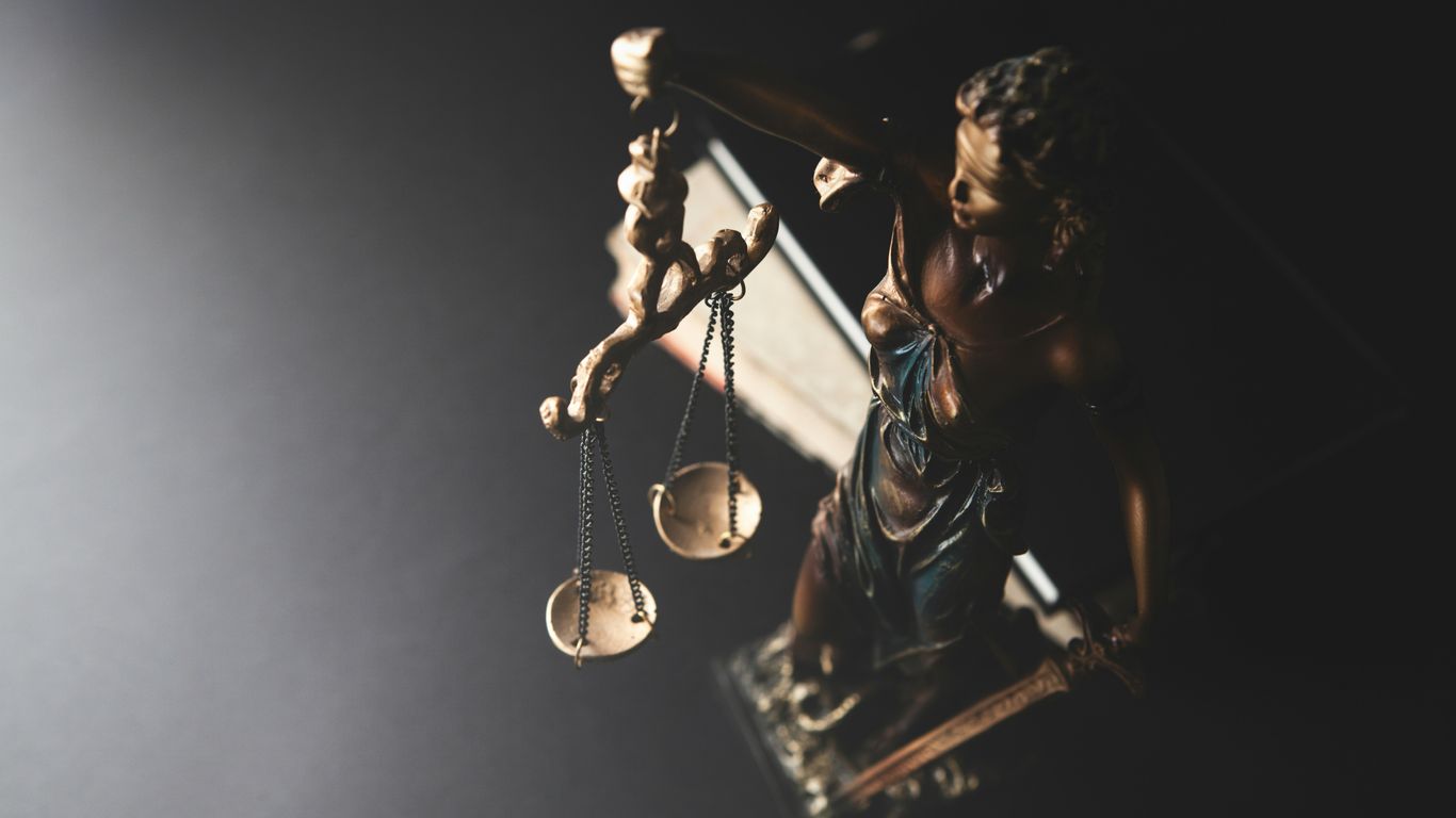 Statue of justice with scales on dark background