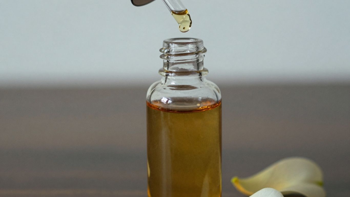 Perfume oil bottle with dropper and flower petal.