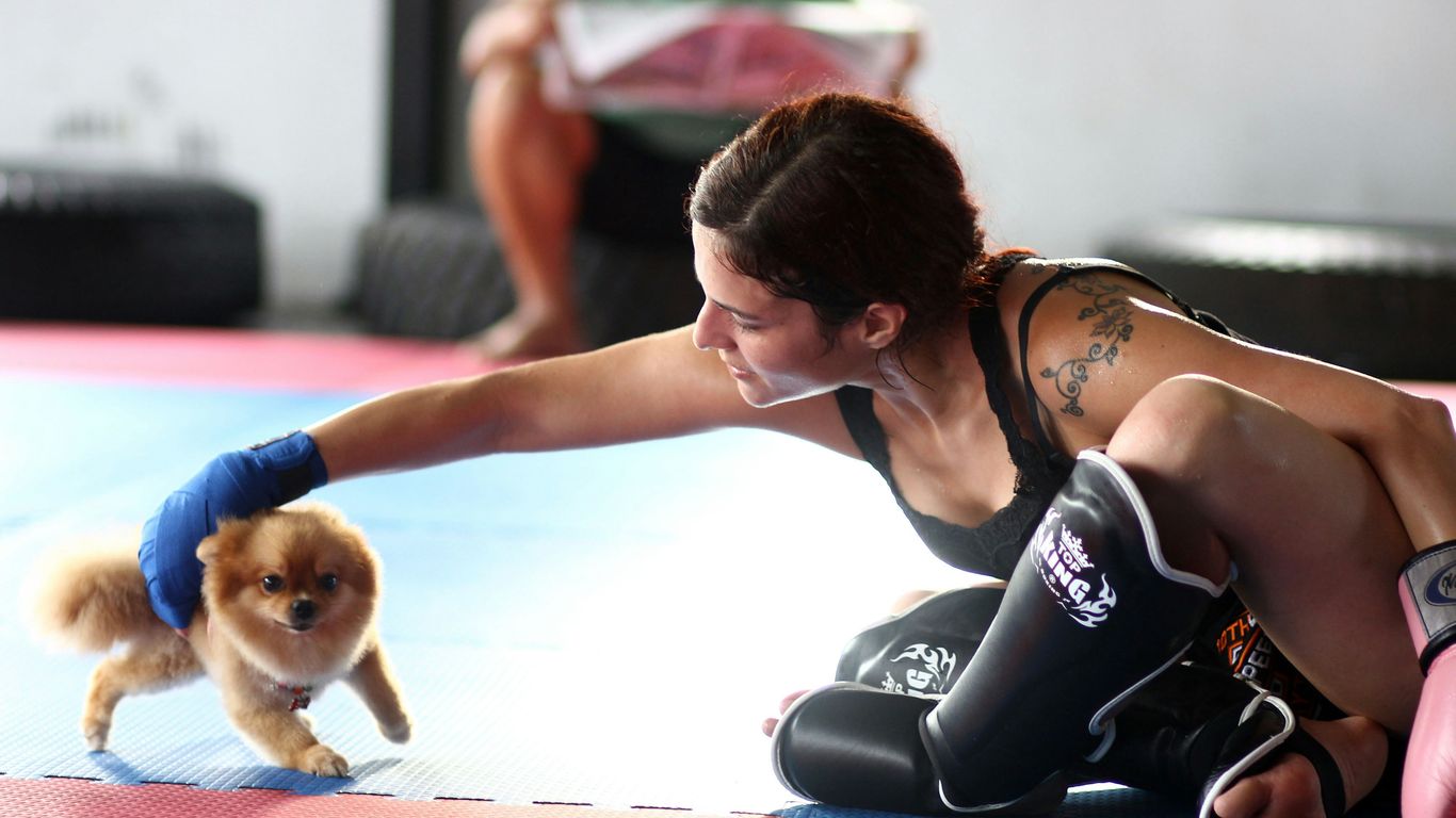 woman in black tank top and black shorts sitting on floor with brown dog