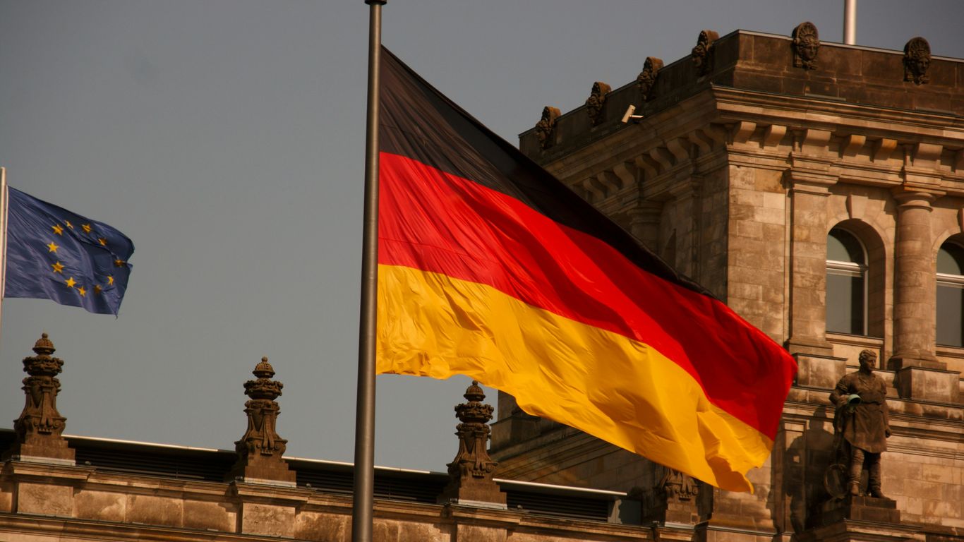 two flags flying next to each other in front of a building