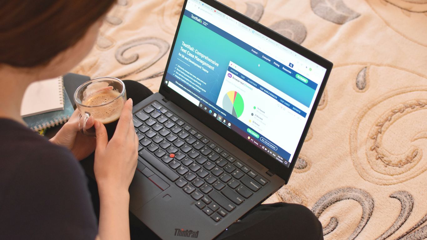 a woman sitting on a bed looking at a laptop