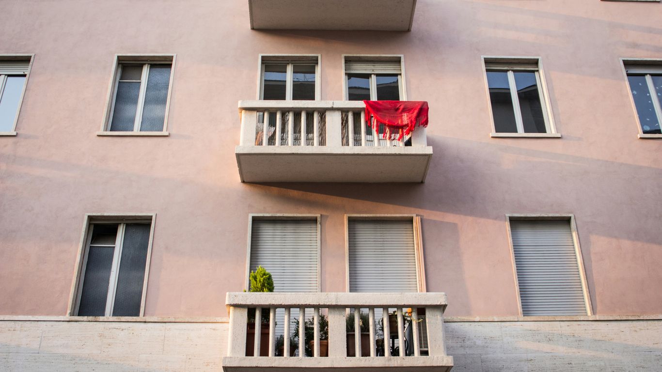 red car parked in front of brown concrete building