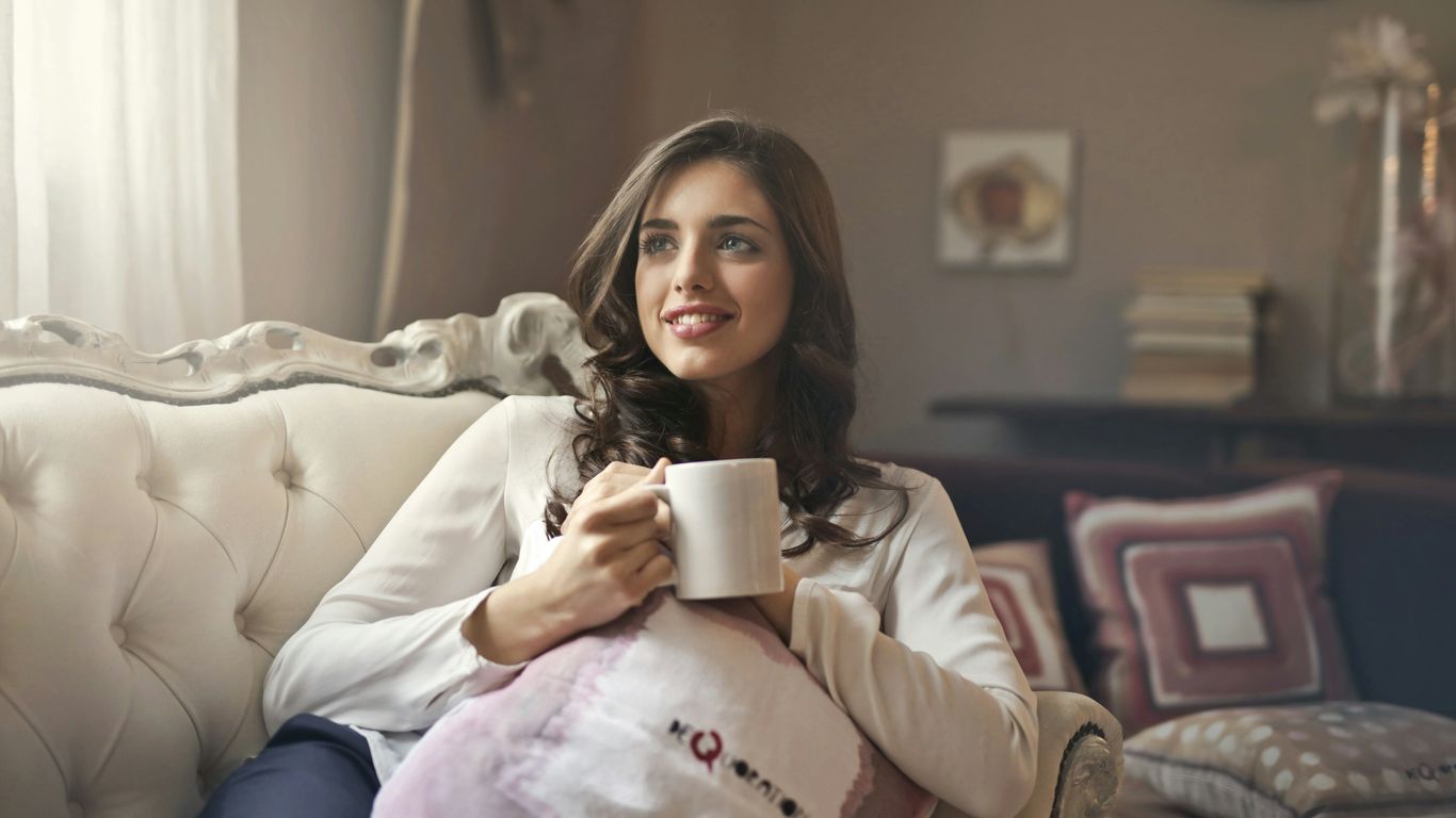 woman holding mug sitting on sofa
