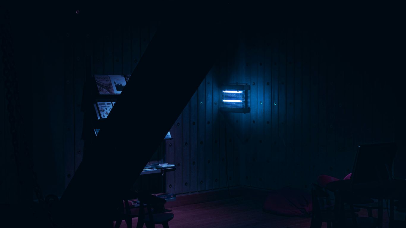 a dark room with a neon light shining on the wall