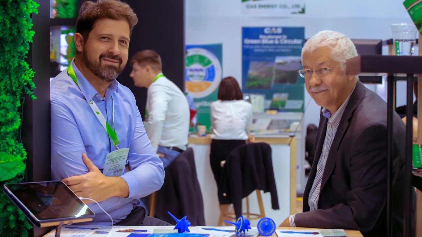 A couple of men sitting at a table with a laptop