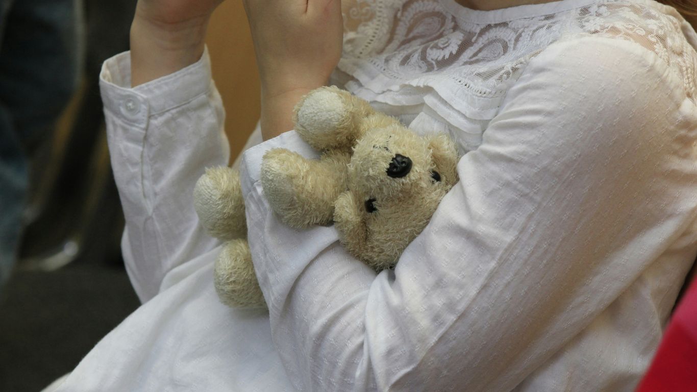 A woman in a white dress holding a teddy bear