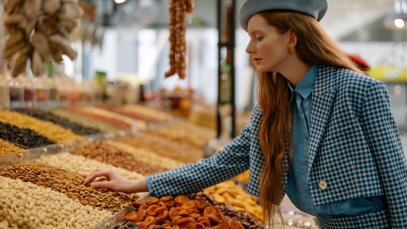 A person shops for nuts and dried fruit at a market.