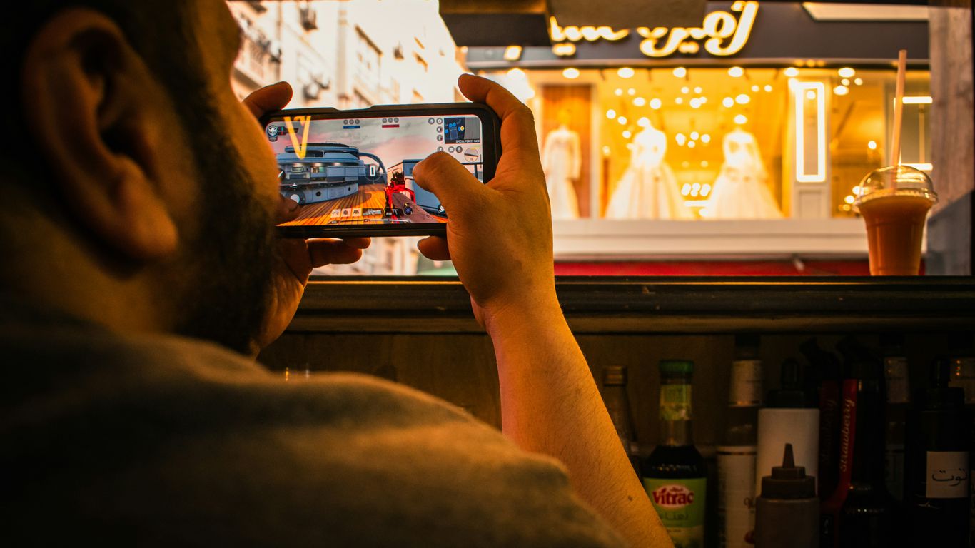 Man films a storefront window display with smartphone.