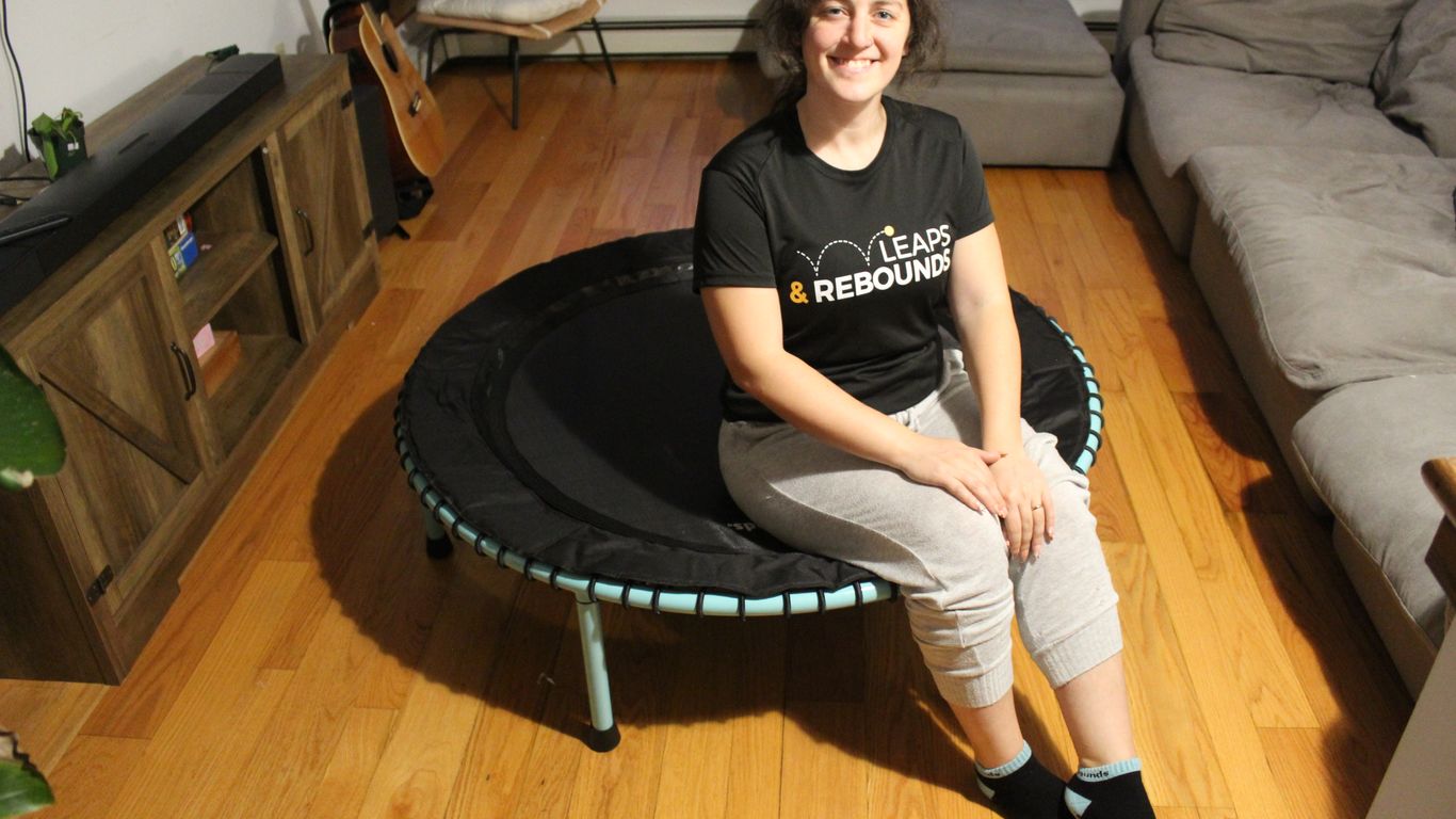 Person sitting on a mini trampoline in a cozy living room.