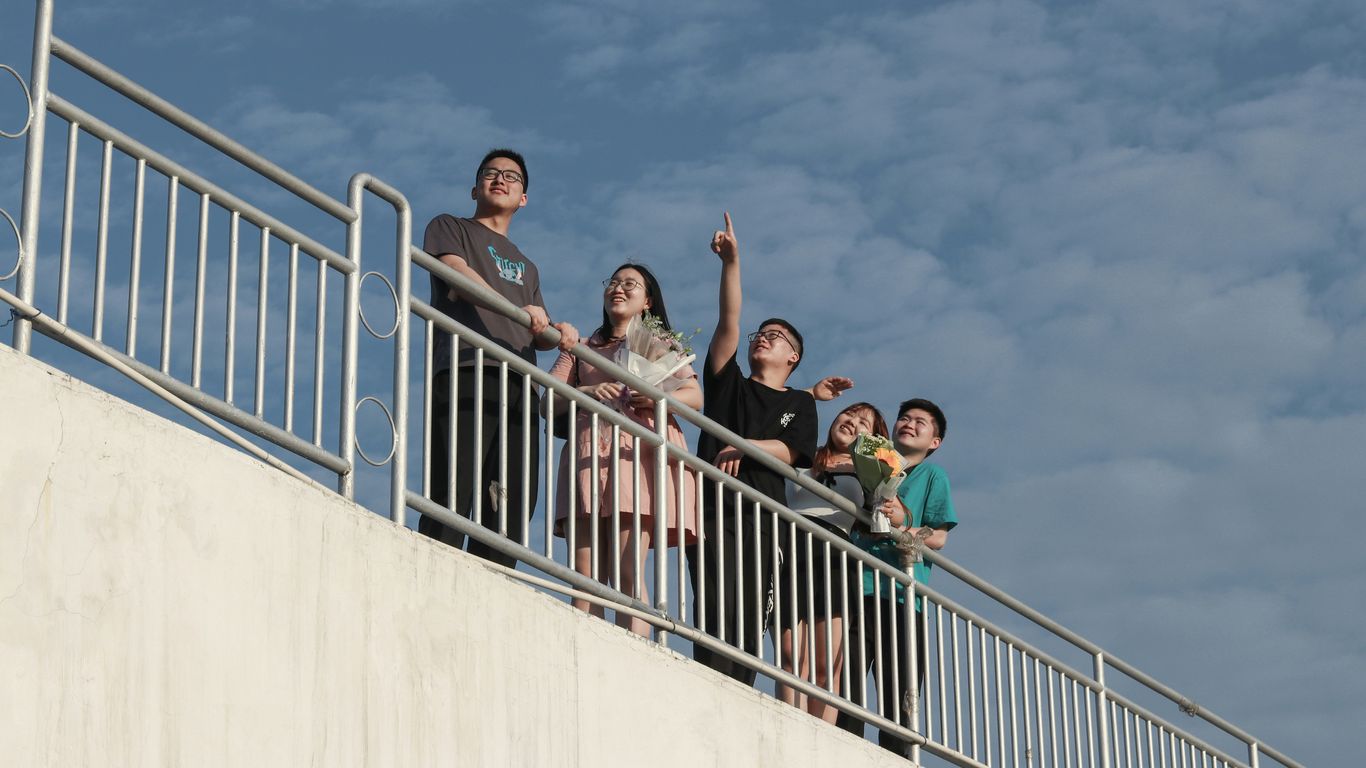 3 men and 2 women standing on white concrete wall during daytime
