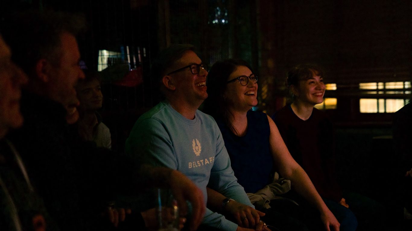 A group of people are laughing and enjoying themselves in a dimly lit room.