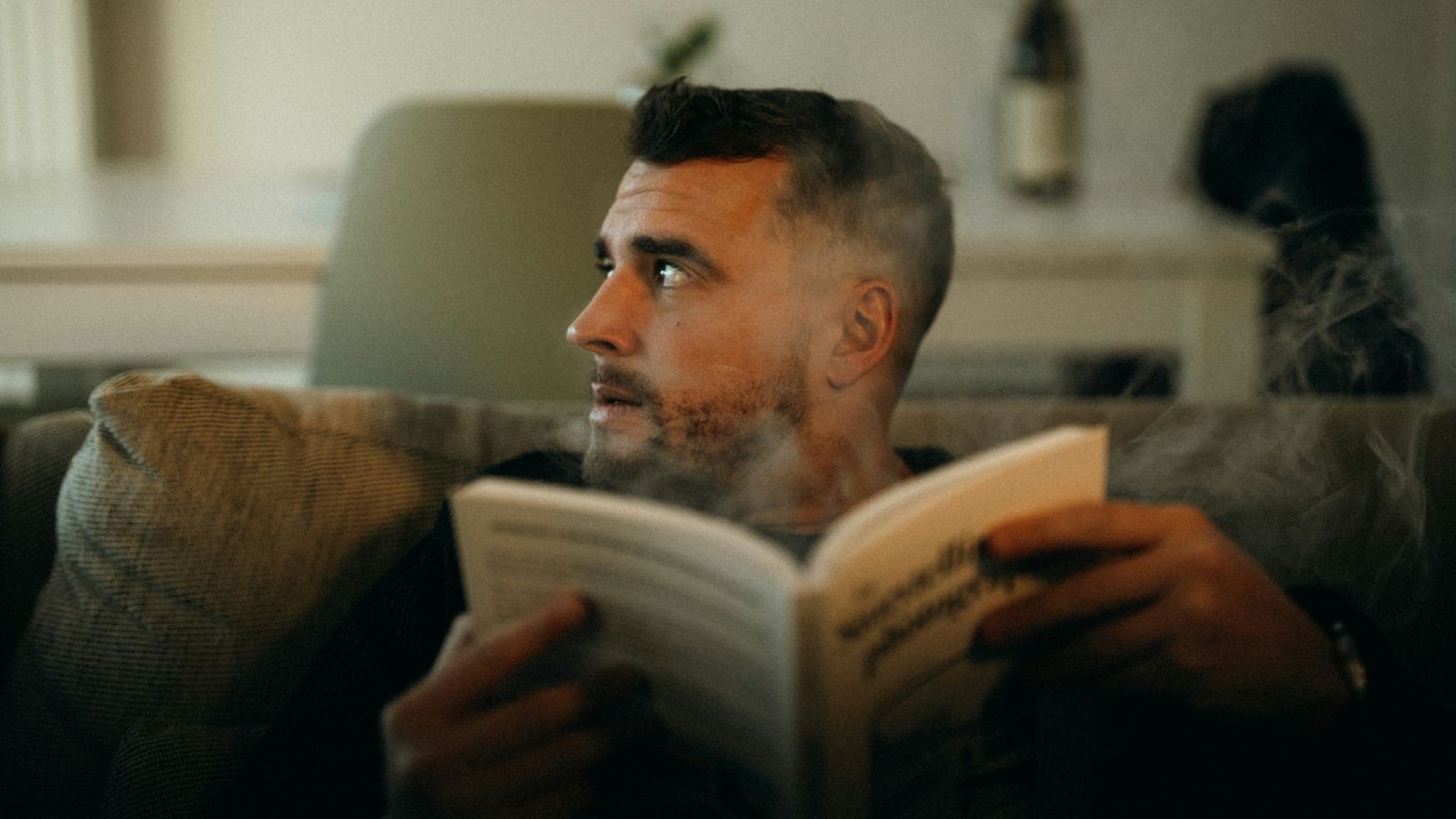 A man sitting on a couch reading a book