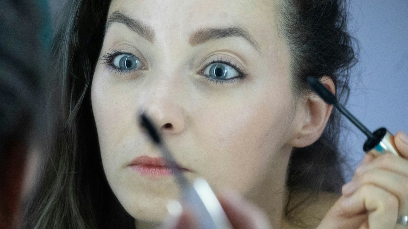 a woman is doing makeup on her face