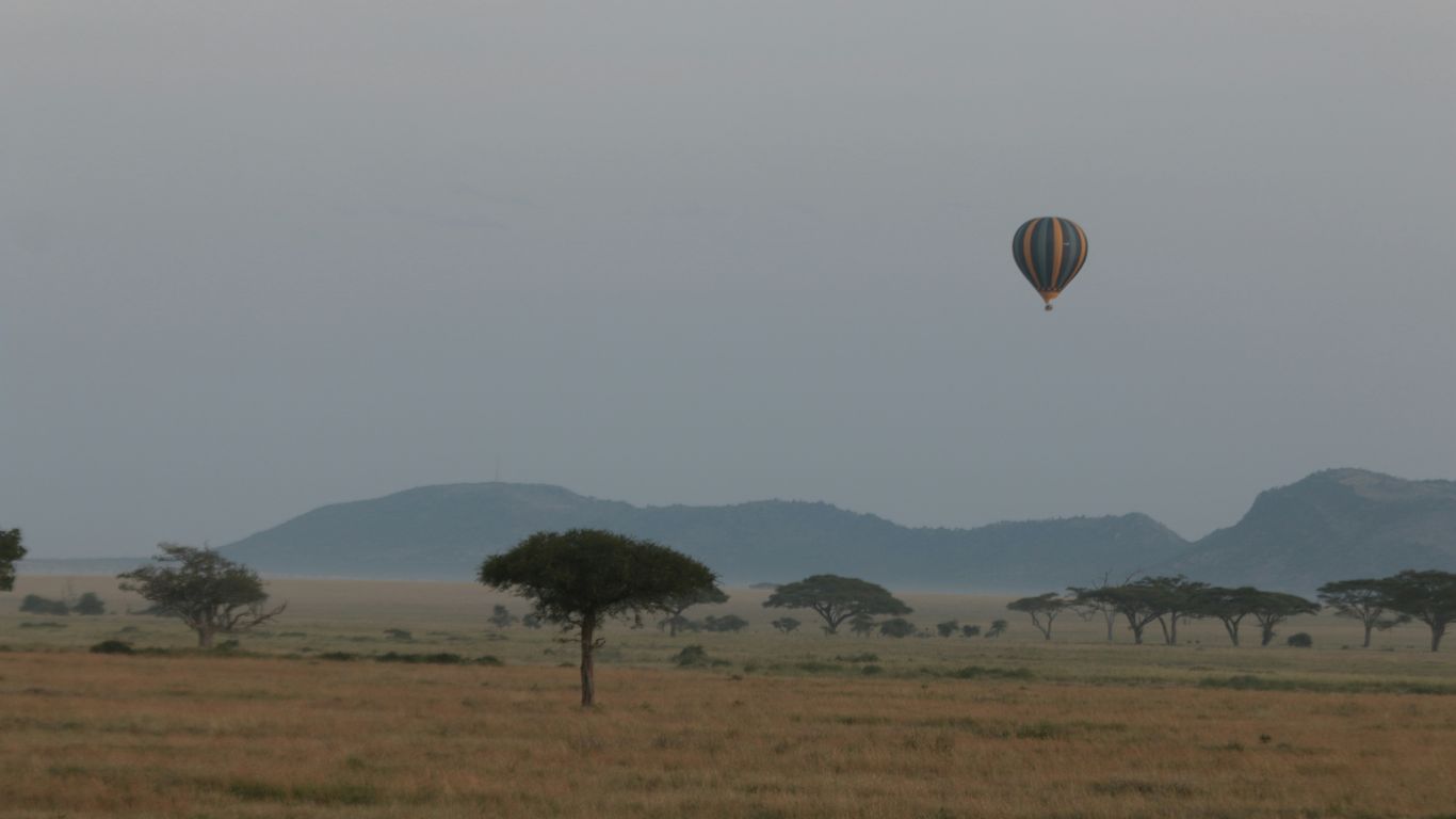 Hot air balloon floats over savanna landscape