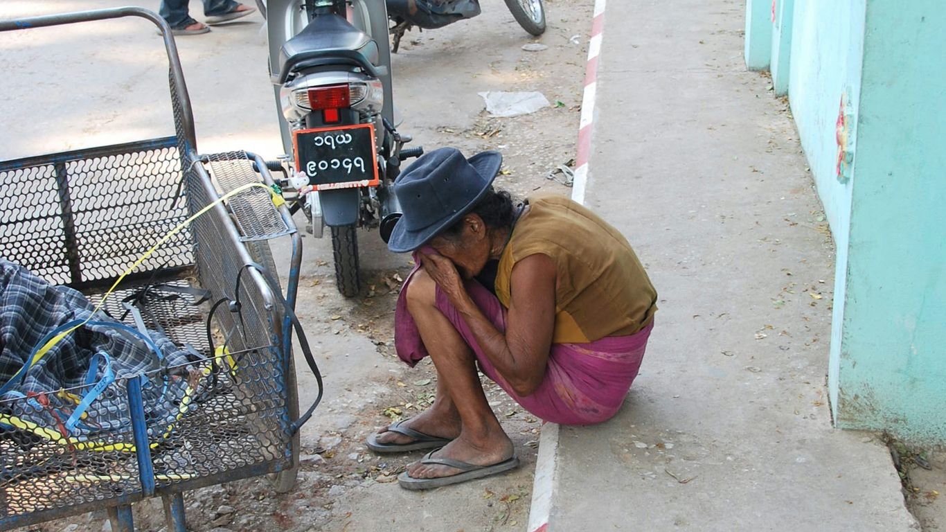 man in brown shirt sitting on gray pavement