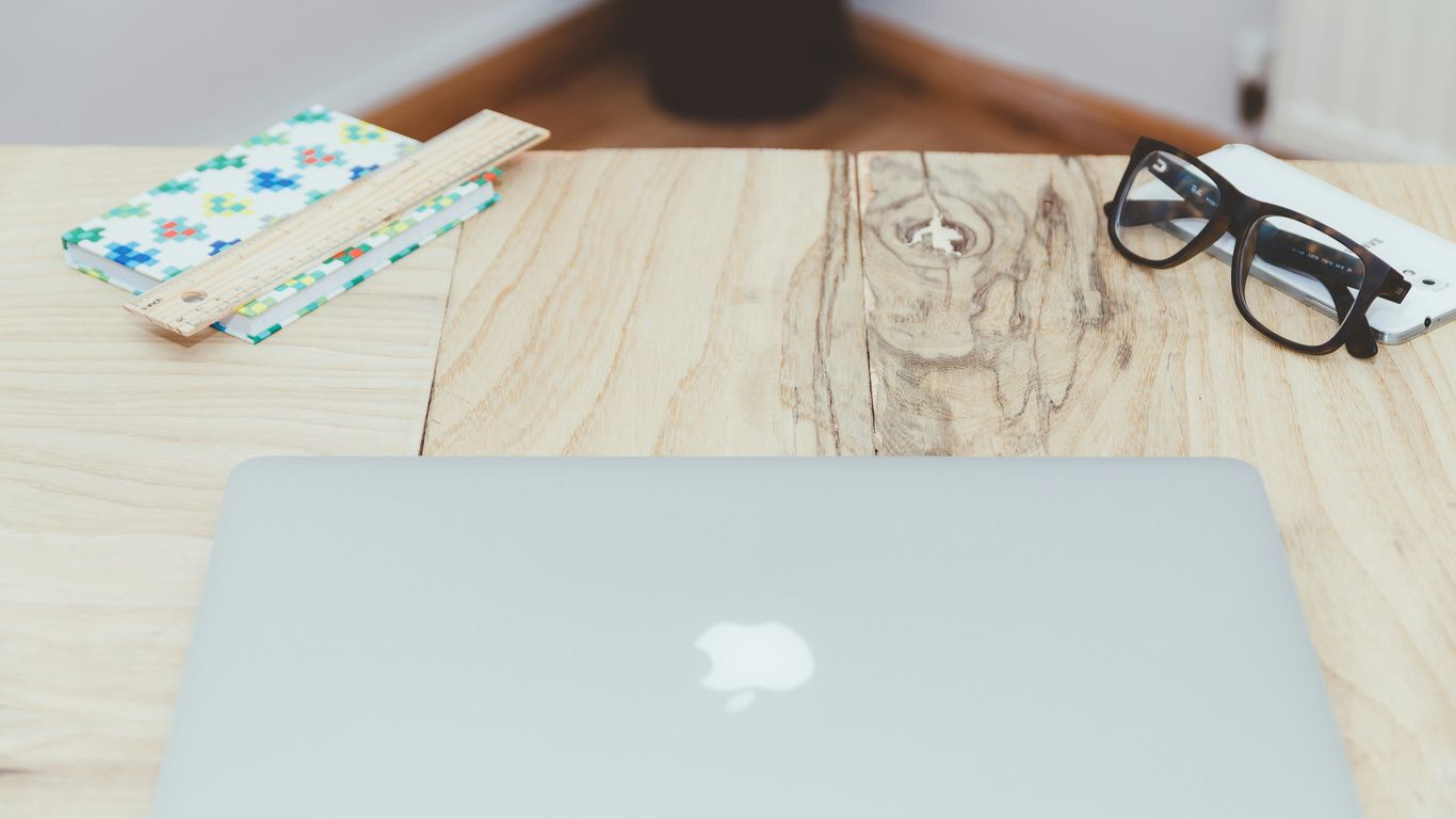 silver MacBook on beige table