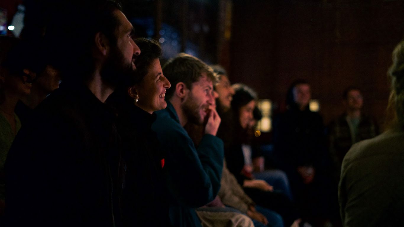 A group of people watching something in a dimly lit room.