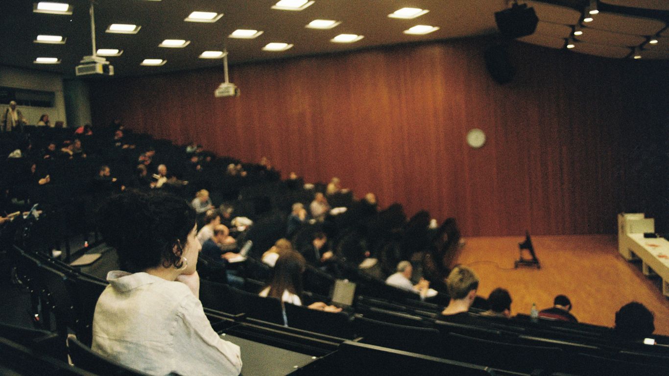 People attend a lecture in a large auditorium.