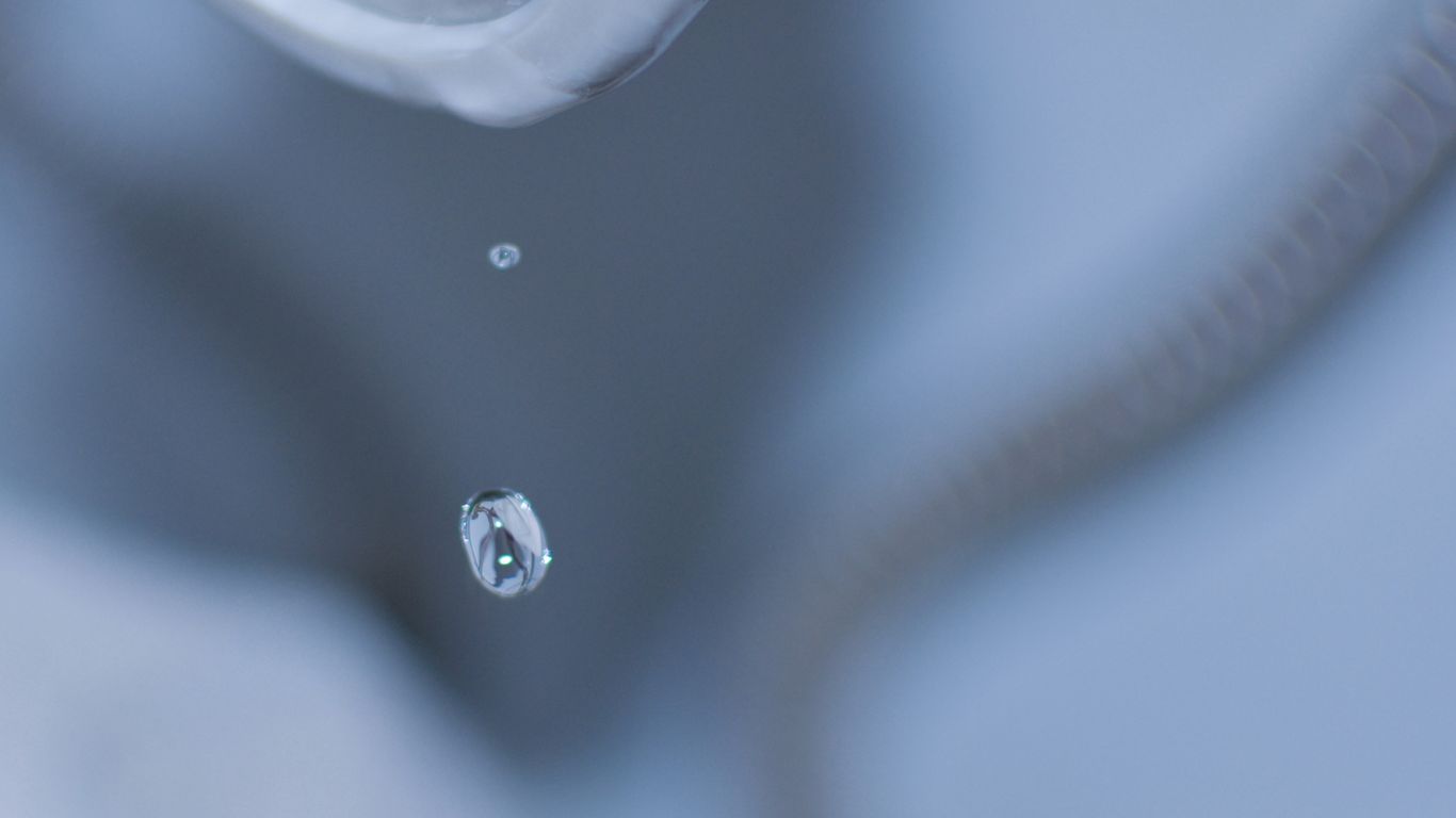 a close up of a sink faucet with a drop of water