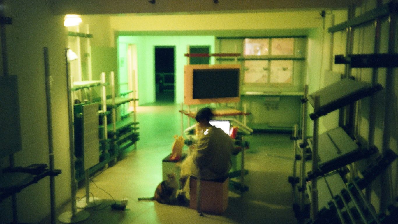 Someone works in a dimly lit, cluttered room.