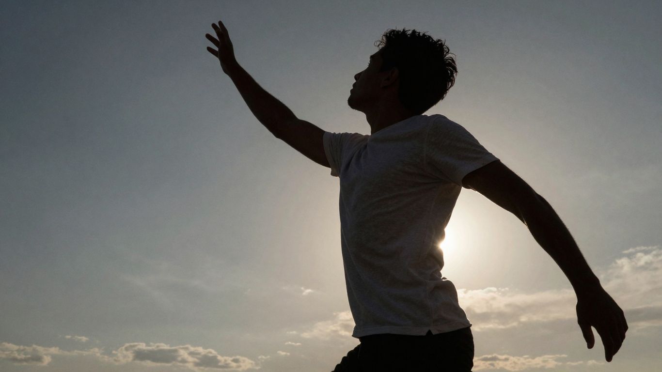 Person reaching upwards, silhouetted against bright background.