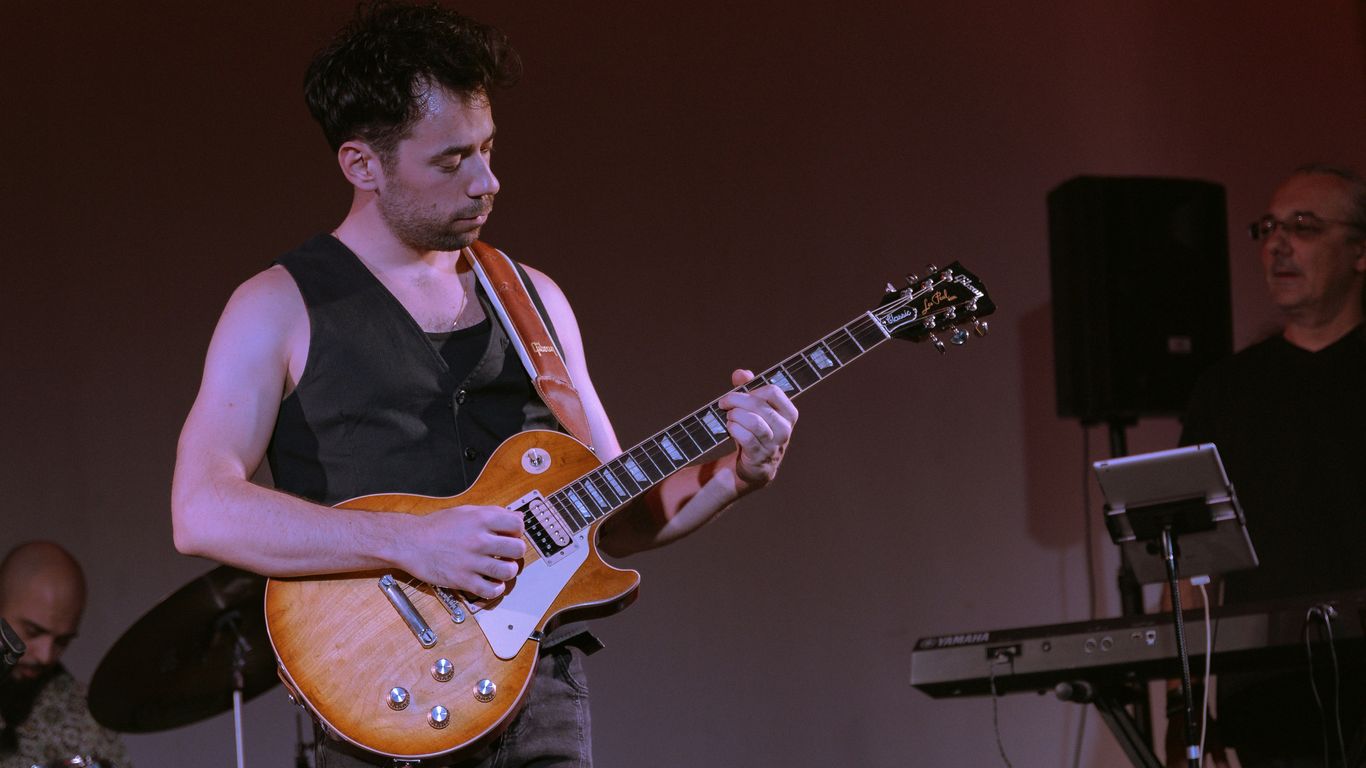 A man standing on a stage playing a guitar