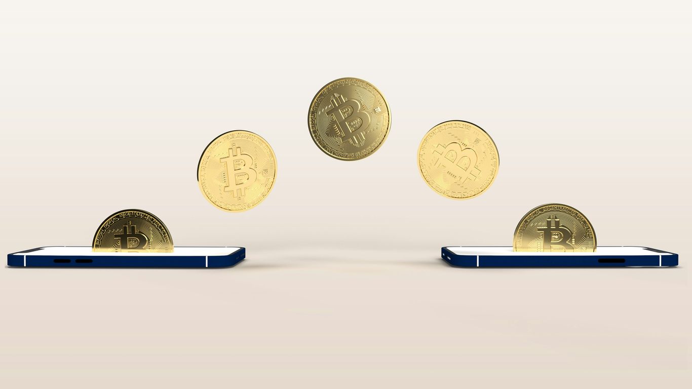 Bitcoin coins transferring between two smartphones. Digital currency concept.