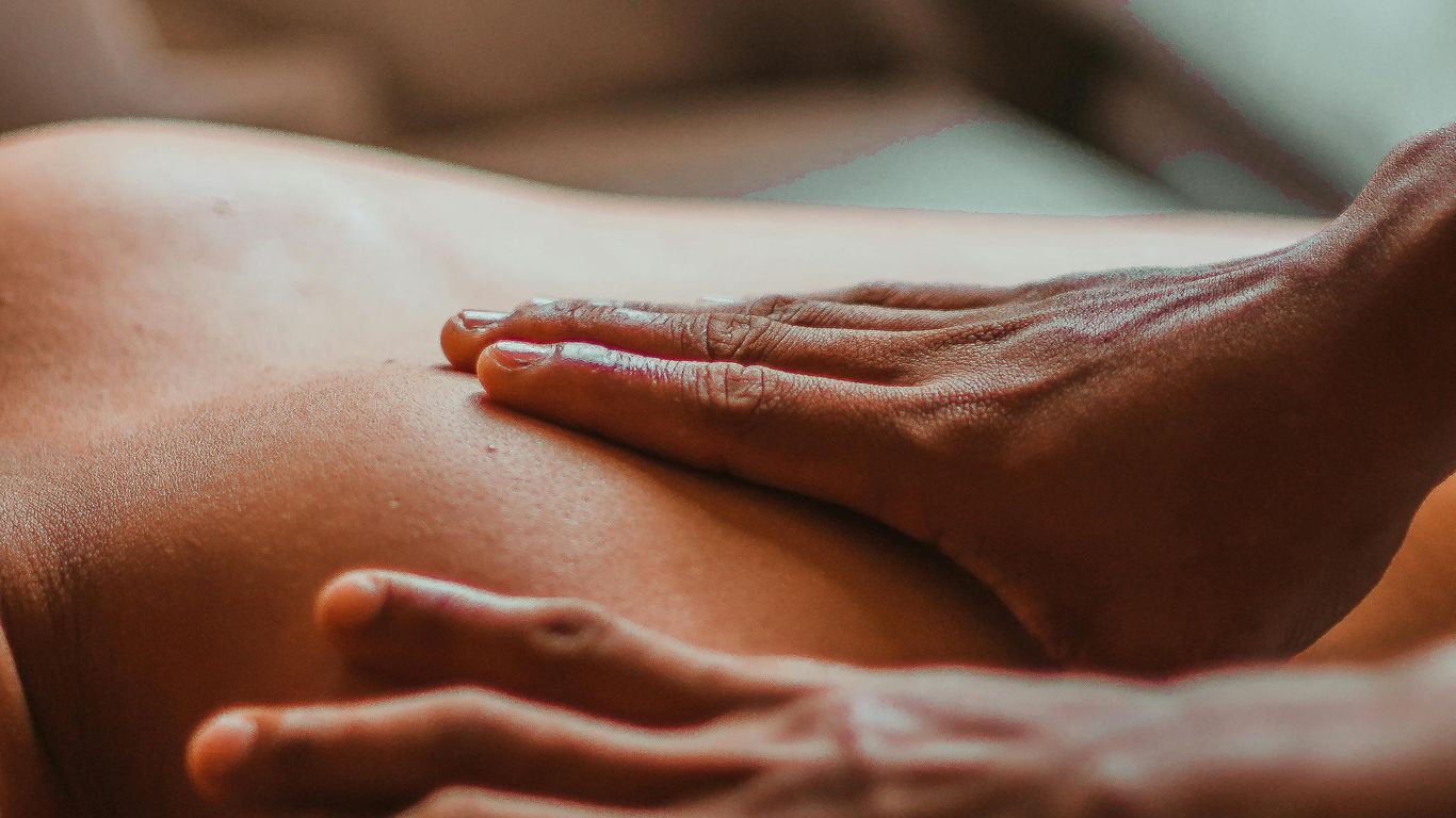 Hands giving a relaxing massage on someone's bare back.