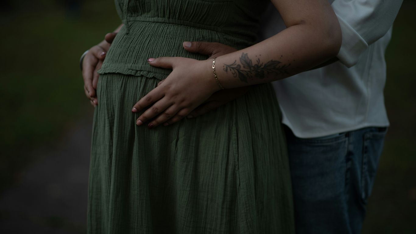 Couple holding pregnant belly outdoors